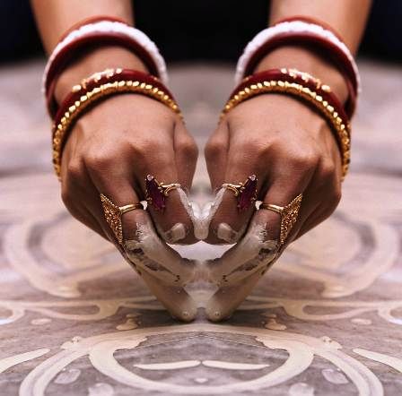 Cultural significance of Shakha Pola worn by bengali women who is drawing alpona